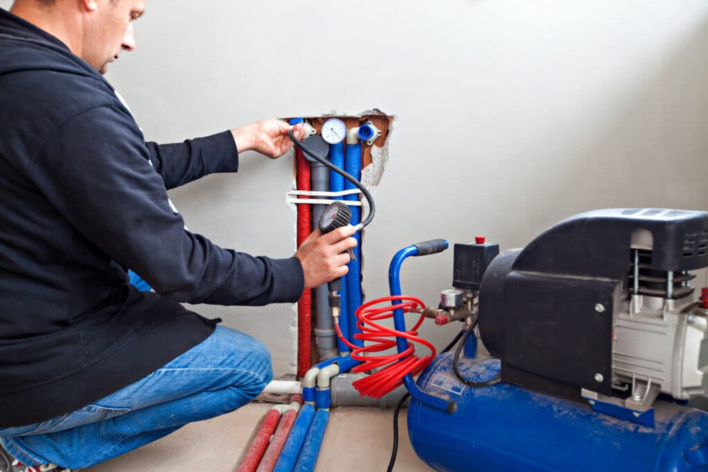 Plumber tests for leaks. Plumber fixing central heating system.